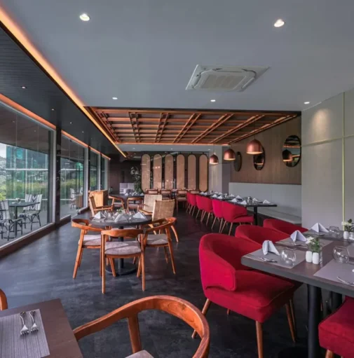 Spacious bar and lounge at Forest Hills Hotel Ciwidey with elegant red chairs, large windows overlooking the hills, and a cozy dining setup.
